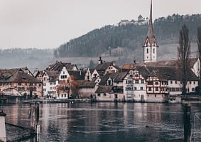 white and brown concrete house beside body of water during daytime